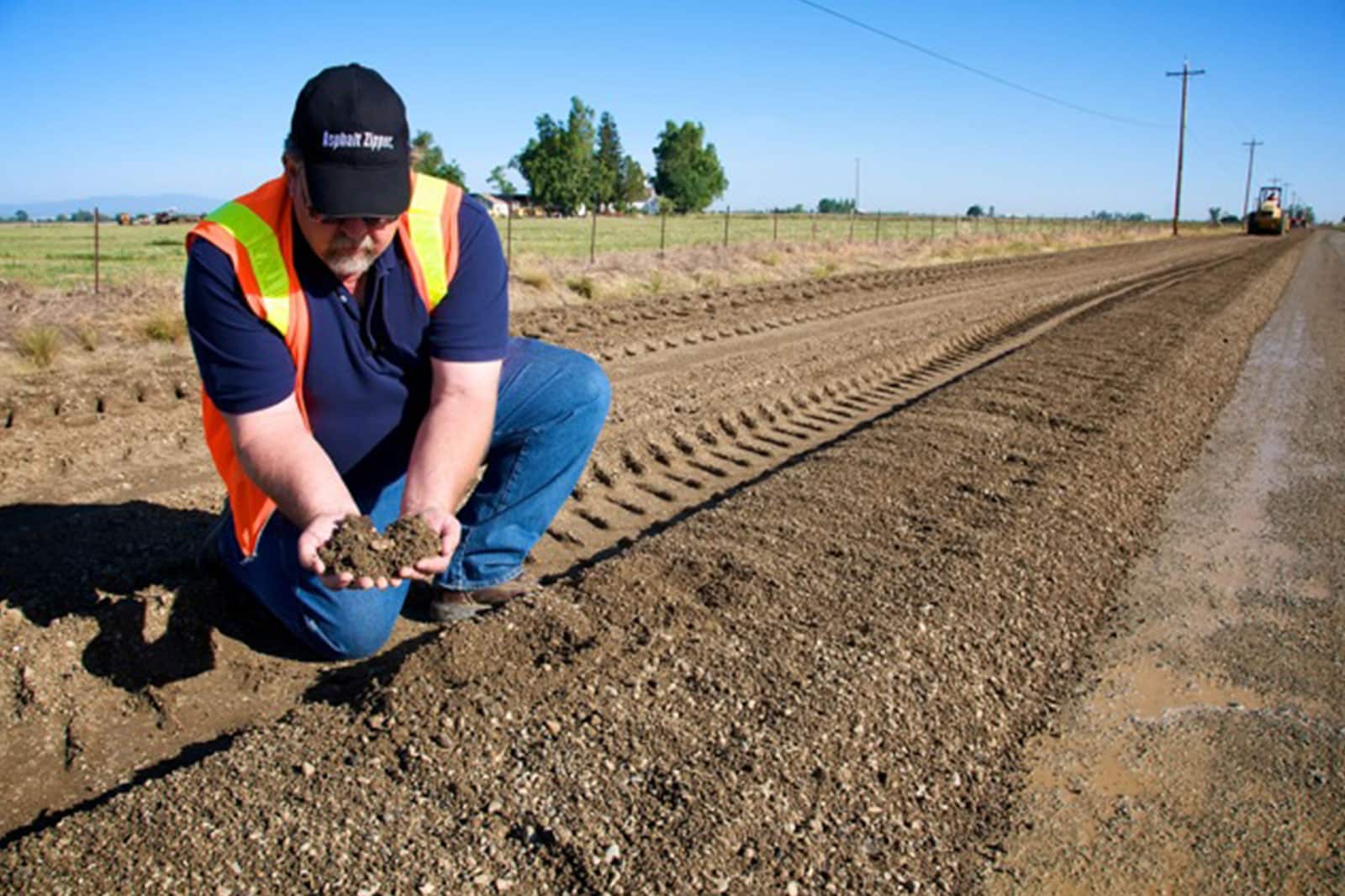 Man holding soil to test on road being graded for new AggreBind implementation