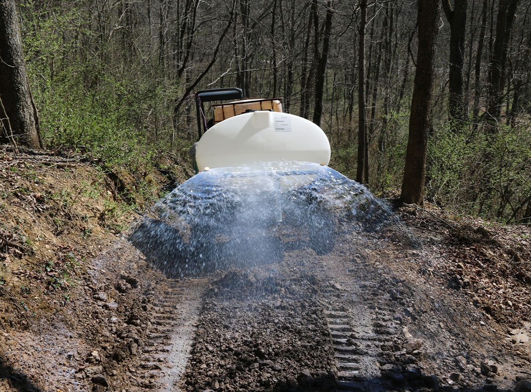 water truck spraying RoadMaster mix on newly cut access road for firefighting vehicles