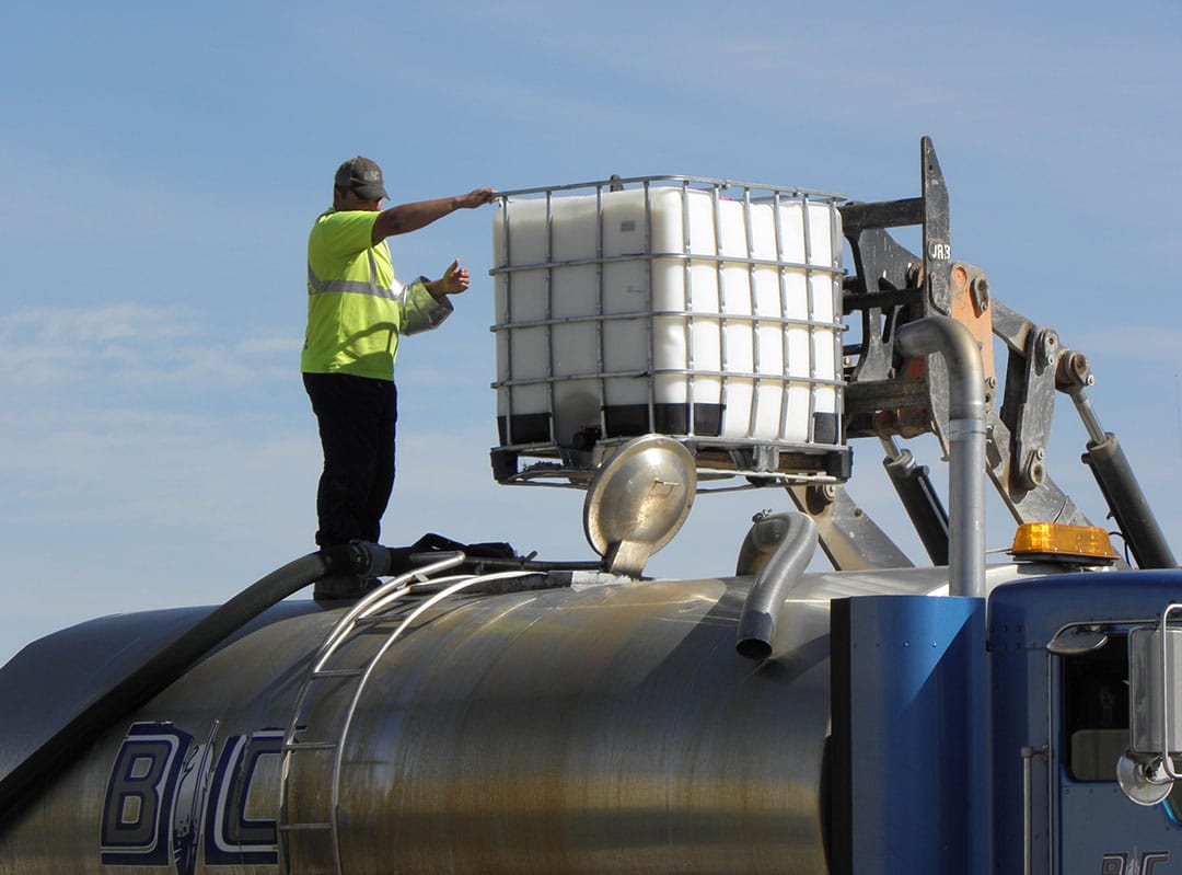 workmen adding AggreBind to water tanker