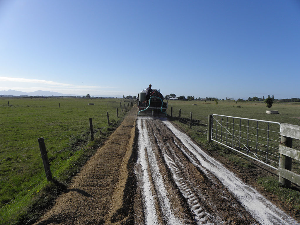 water truck on a farm road spraying AggreBind