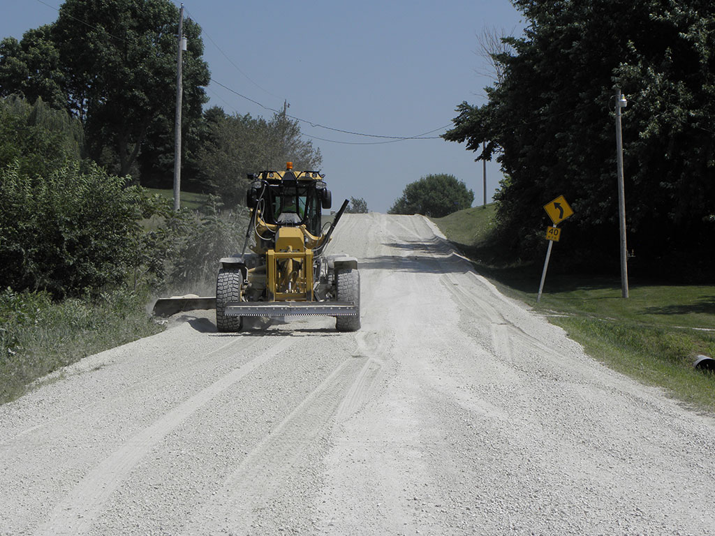 grader on a dirt road prepping for AggreBind project