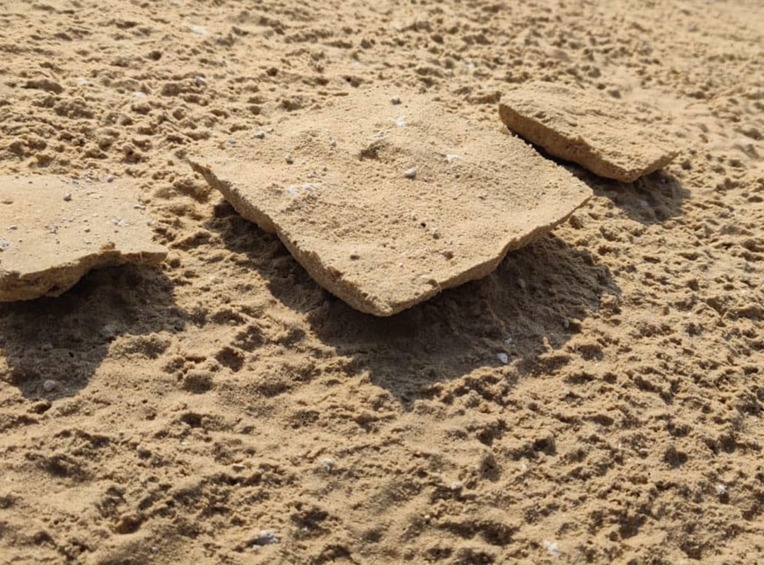 Solid squares of AggreDust crust cut from desert port project sitting on sand